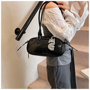 Detail of glossy black leather shoulder bag with silver hardware and metallic pendant