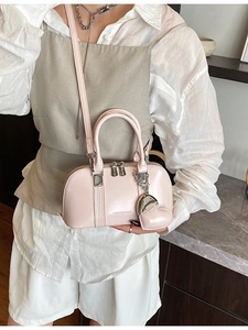 Pink shell handbag with heart charm and shoulder strap shown in lifestyle scene