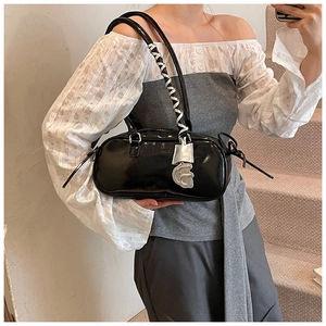 Detail of black glossy patent leather shoulder bag with silver hardware and braided strap