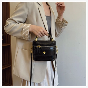 Elegant black quilted leather box bag featuring a gold camellia flower and metal handle