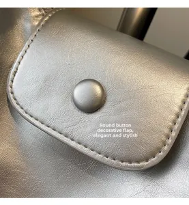 Detail of silver faux leather bag featuring a round button flip cover and precise stitching