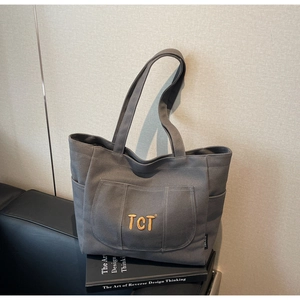 Close-up of deep grey canvas tote bag featuring front pocket and detailed embroidery