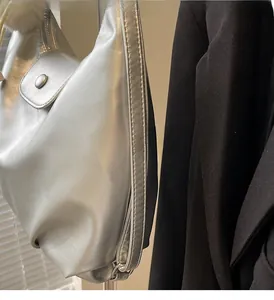 Detail of silver metallic PU leather shoulder bag with side zipper and button pocket