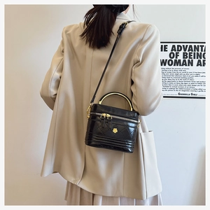 Detail of classic black quilted shoulder bag with golden camellia hardware and metal handle