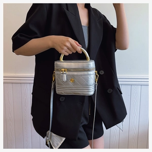 Detail of silver quilted box bag with golden rose logo and metallic top handle