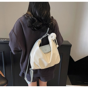 Vue détaillée du sac hobo crème avec rabat bleu clair et breloque en fourrure blanche