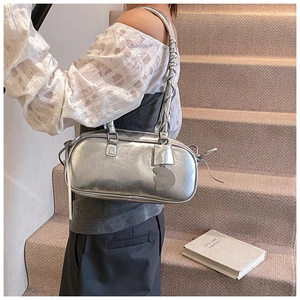 Detail of silver metallic baguette bag with wrinkled texture and spiral shoulder strap