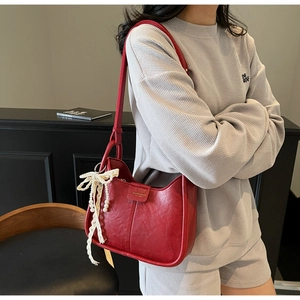 Detail of red vintage leather shoulder bag with elegant lace pearl bow charm