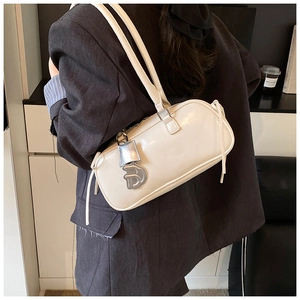 Detail of cream white leather baguette bag with a stylish metal D-letter charm