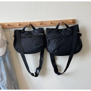 Detail of black nylon tote bag with adjustable strap and brand label on coat rack