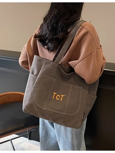 Large dark grey canvas tote bag with TCT embroidery shown on a model's shoulder