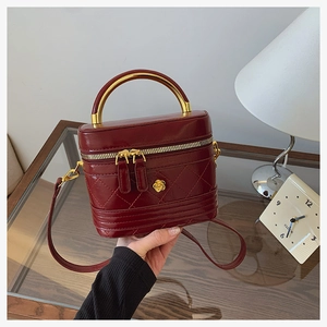 Close-up of burgundy quilted crossbody bag with luxury gold curved metal handle