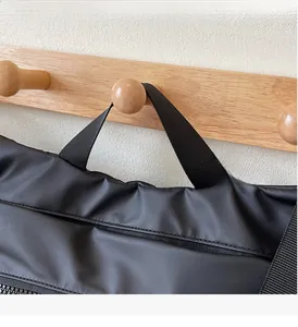 Detail of durable black nylon tote handle with reinforced stitching and zipper closure