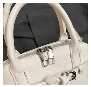 Detail of white lychee leather texture and silver double zippers on the handbag