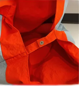 Detailed macro view of the metal snap button and reinforced stitching on a tote bag