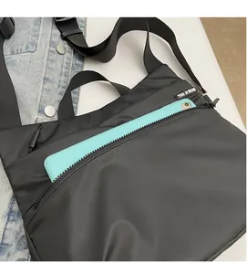 Macro shot of black nylon crossbody bag featuring large front zipper pocket for tablets