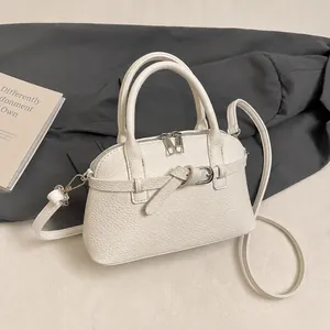 Detail shot of the textured white lychee leather handbag with silver metal hardware accents