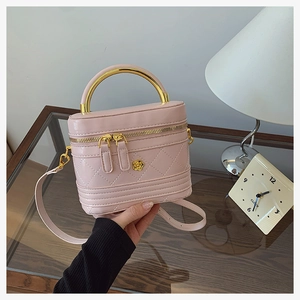 Close-up of pink quilted box bag featuring golden metal handle and flower emblem