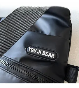 Detail view of black nylon crossbody bag featuring sturdy zipper and logo rubber patch