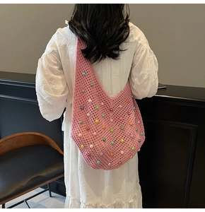 Pink crochet tote bag with colorful beads shown from a side view on a model