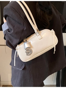 White PU leather baguette bag with metal D charm shown on shoulder for fashion styling