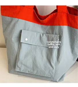Detail of orange and blue tote bag showing soft textured fabric and metal snap pockets