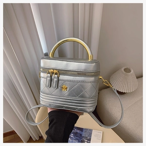Close-up of silver quilted box bag with golden camellia hardware and U-shaped metal handle