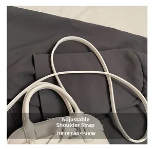 Detail of white lychee leather handbag showing adjustable strap and round handle