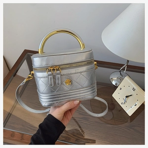 Detail view of silver quilted crossbody bag with gold metal handle and floral emblem