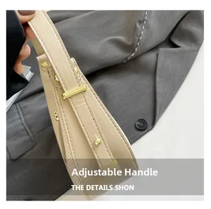 Detail einer hellbeigen Lederhandtasche mit verstellbarem Riemen und goldener Schnalle