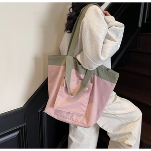 Detailed side view of large nylon tote bag in pink and green on female model