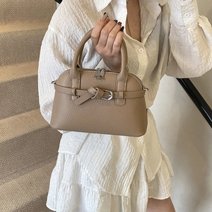 Detail of khaki Boston handbag showing litchi texture and buckle knot design