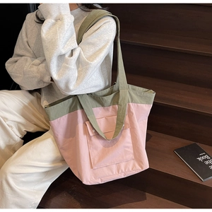 Detail of olive green and pink canvas tote bag showing the buckled pocket and woven straps
