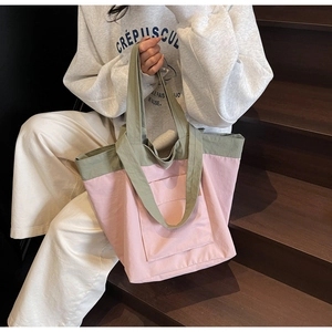 Detail of a color-block tote bag in green and pink with a large exterior front pocket