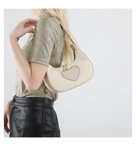 Detail of beige woven heart crescent bag with gold ball zipper and textured finish