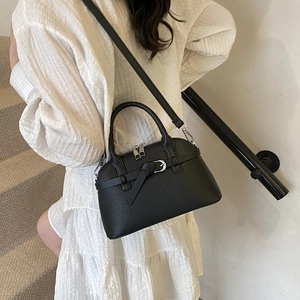 Rear view of model wearing a black litchi pattern shell bag with silver buckle detail