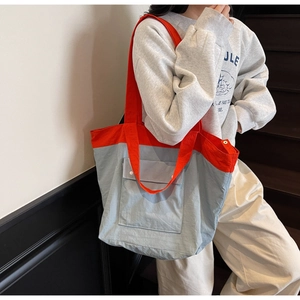 Detail of color-block tote bag with large front pocket and wide shoulder strap