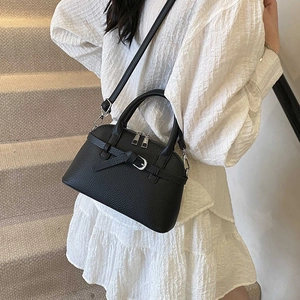 Close-up of black lychee texture leather handbag with silver zippers and belt buckle detail