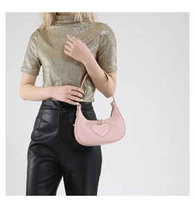 Close-up of pink heart-shaped underarm bag with embossed texture and gold bead zipper detail