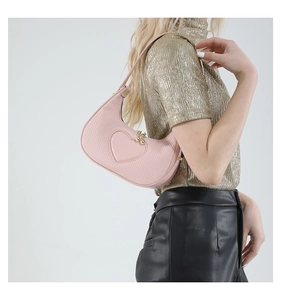 Pink crescent underarm bag with woven texture and heart patch worn by a model