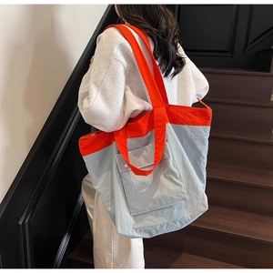 Lifestyle shot of large contrast tote bag with front pocket showing casual shoulder fit