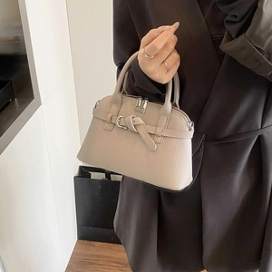 Detail of beige satchel bag with litchi grain texture and silver metal buckle