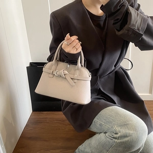 Detail of beige lychee grain leather handbag with silver zipper and buckle