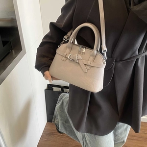Detail of beige pebbled leather handbag with silver hardware and double zipper closure