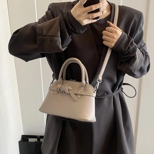 Close-up of beige lychee grain handbag featuring decorative buckle knot and silver hardware