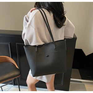 Nahaufnahme der schwarzen Tote-Bag aus Leder mit Lychee-Maserung und vorderer Druckknopftasche