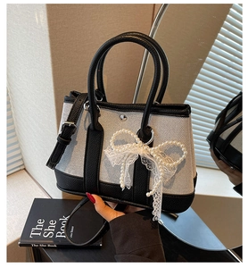 Detailed shot of black and white contrast handbag with pearl lace bow decoration