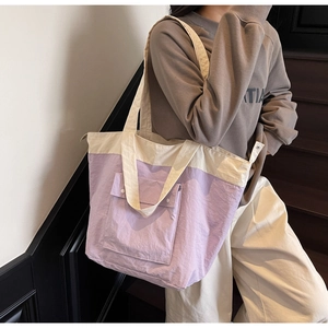 Detail of light purple and cream large tote bag with a snap-button front pocket and fabric handle