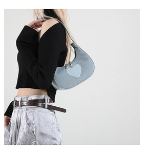 Light blue heart-shaped shoulder bag shown on model with textured denim finish