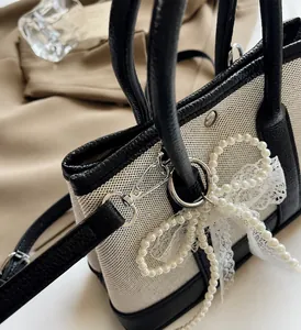 Detail of contrast tote bag with mesh fabric, black leather trim and pearl bow charm
